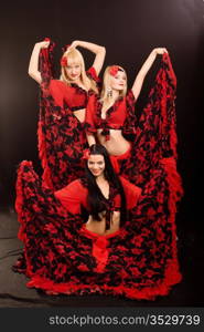 Three beautiful girls in Gipsy suits on a black background
