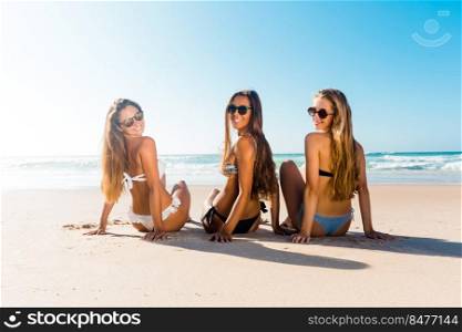 Three beautiful girls on the beach and looking back