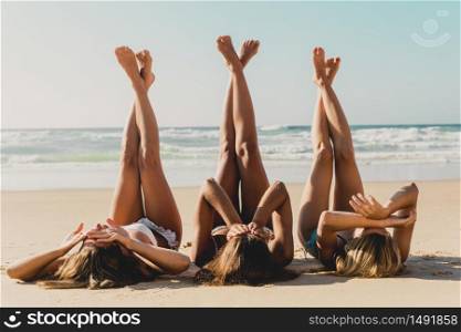 Three beautiful girls on the beach lying on the sand