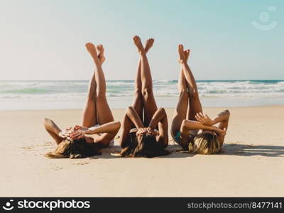 Three beautiful girls on the beach lying on the sand