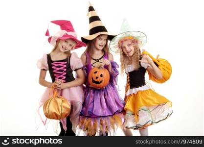 Three Beautiful Smiling Little Girls with Long Hair in the Colorful Witch Costume Looking at Camera with Trick or Treat Bags and Jack O&rsquo; Lantern.