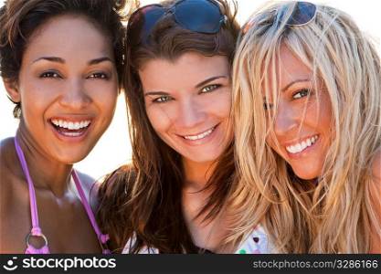 Three beautiful young women in their twenties laughing and having fun at a beach, shot in golden evening sunshine.