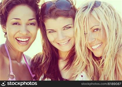 Three beautiful young women in their twenties laughing and having fun at a beach, shot in golden evening sunshine.
