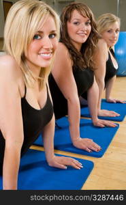 Three beautiful young women stretching at the gym