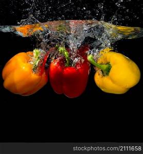 three bell peppers falling into splash water