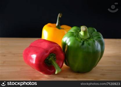 Three bell peppers on a wooden background