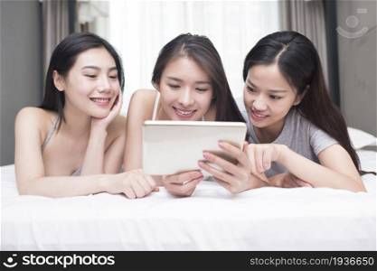 Three best friends lying on the bed and looking at the tablet