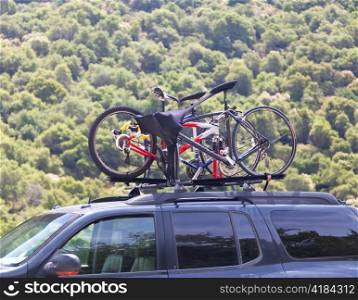 Three bicycles on the top of offroad car near forest