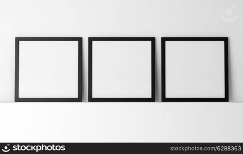 three blank black photo frames on white shelf