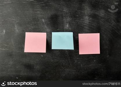 three blank paper stickers are stuck to a black wooden board, copy space