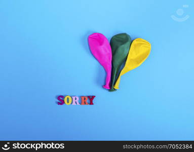 three blow off balloons and the word sorry on a blue background