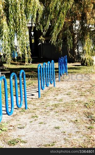 Three blue bike stands in a park in the fall.