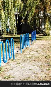 Three blue bike stands in a park in the fall.