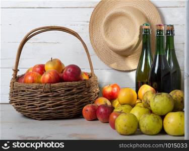 three bottles of cider and a basket of apples