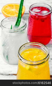 Three bottles of drinks from aloe,orange, and cranberries in a light tone