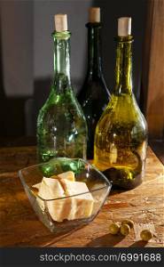 three bottles of olive oil and parmesan cheese on a wooden surface