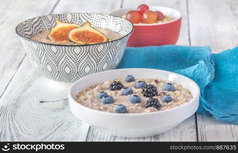 Three bowls of oatmeal with different berry and fruit toppings: top view