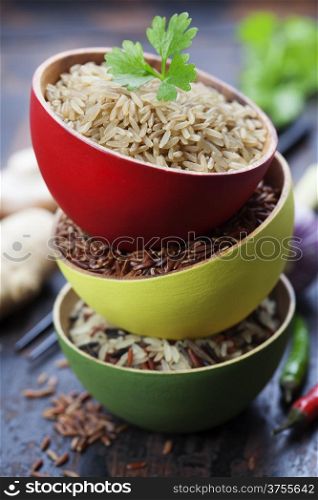 Three bowls with different types of rice on wooden background