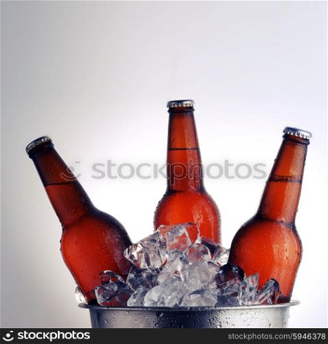 Three brown beer bottles in ice bucket with condensation