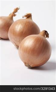 Three brown onions on white background