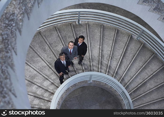 Three business associates standing on spiral staircase, portrait