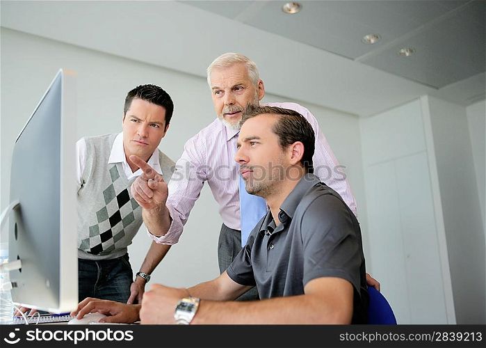 Three business colleagues gathered around computer
