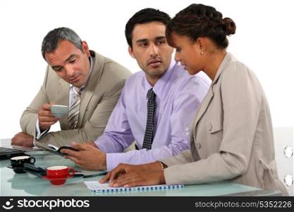 Three business people having coffee during meeting