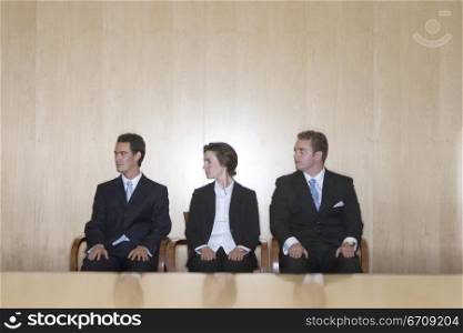 Three business people looking in the same direction while sitting together