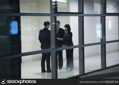 Three business people meeting, seen through glass wall