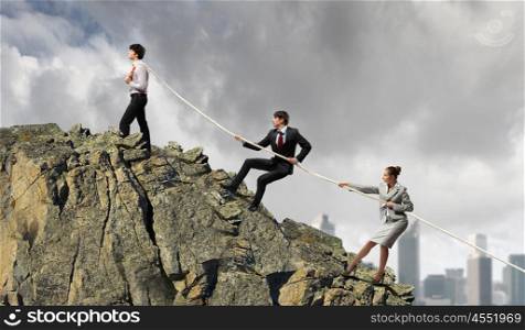 Three business people pulling rope. Image of three businesspeople pulling rope against city background