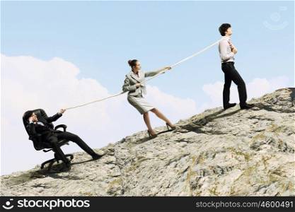 Three business people pulling rope. Image of three businesspeople pulling rope atop of mountain