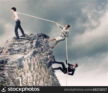 Three business people pulling rope. Image of three businesspeople pulling rope atop of mountain