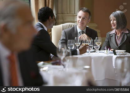 Three business people sitting at restaurant table talking