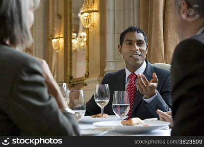 Three business people sitting at restaurant table talking