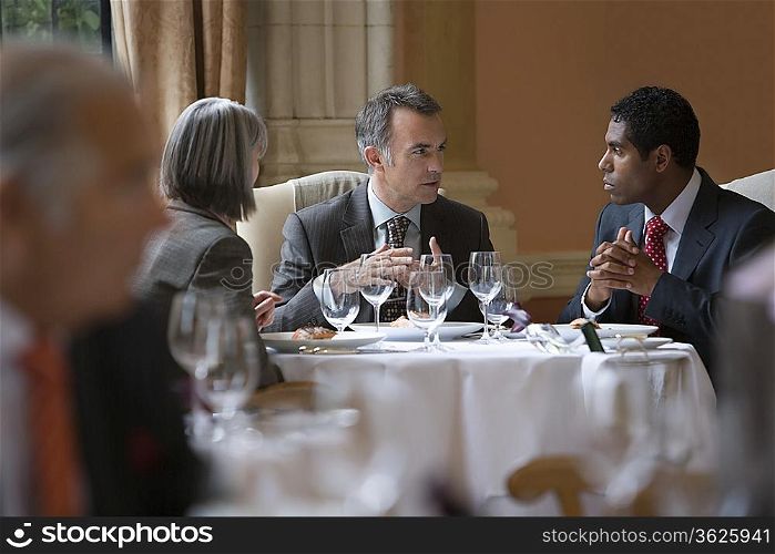 Three business people sitting at restaurant table talking