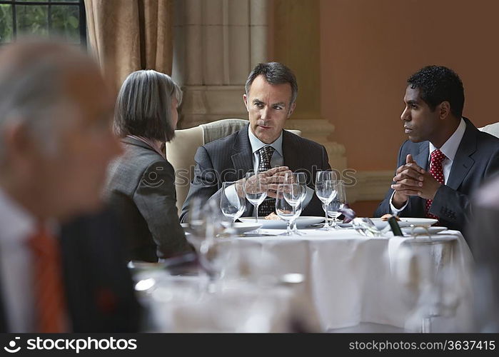 Three business people sitting at restaurant table talking