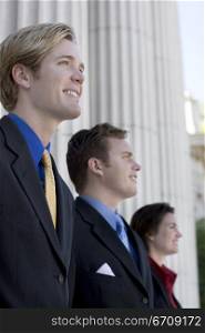 Three Business people standing together in front of the columns and smiling