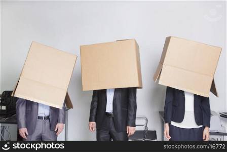 Three business people with boxes over their heads in an office