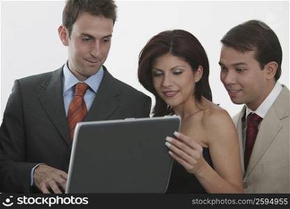 Three businessmen and a businesswoman looking at a laptop