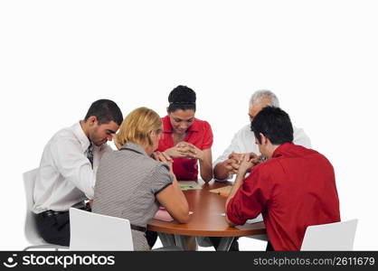 Three businessmen and two businesswomen praying in a meeting