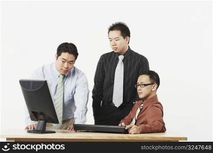 Three businessmen looking at a computer monitor