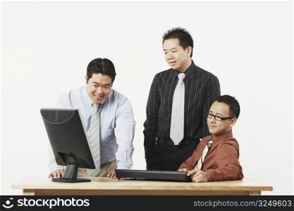Three businessmen looking at a computer monitor