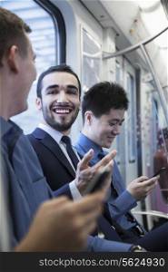 Three businessmen sitting in a row and talking on the subway