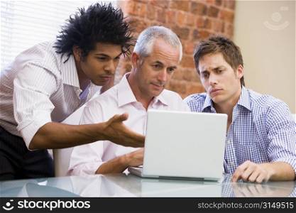 Three businessmen sitting in office with laptop