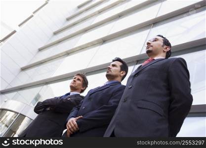 Three businessmen standing outdoors by building (high key/selective focus)