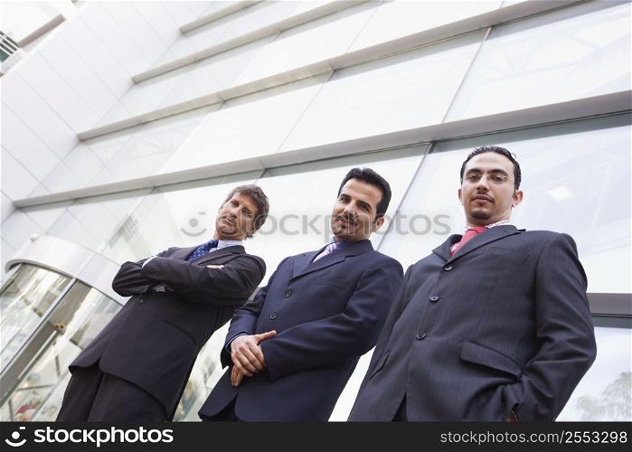 Three businessmen standing outdoors by building (high key/selective focus)