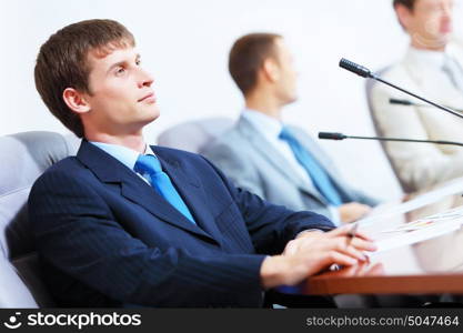 Three businesspeople at meeting. Image of three businesspeople at table at conference