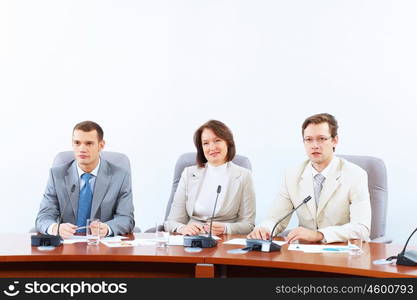 Three businesspeople at meeting. Image of three businesspeople sitting at table at conference