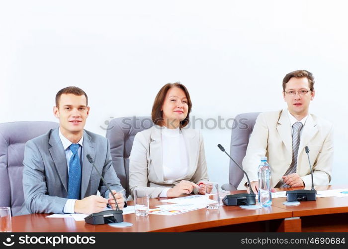 Three businesspeople at meeting. Image of three businesspeople sitting at table at conference