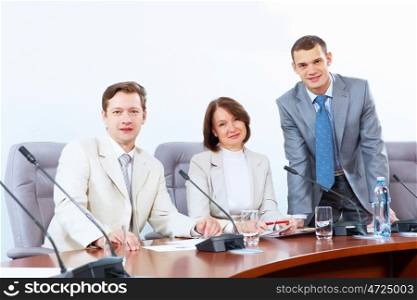 Three businesspeople at meeting. Image of three businesspeople sitting at table at conference